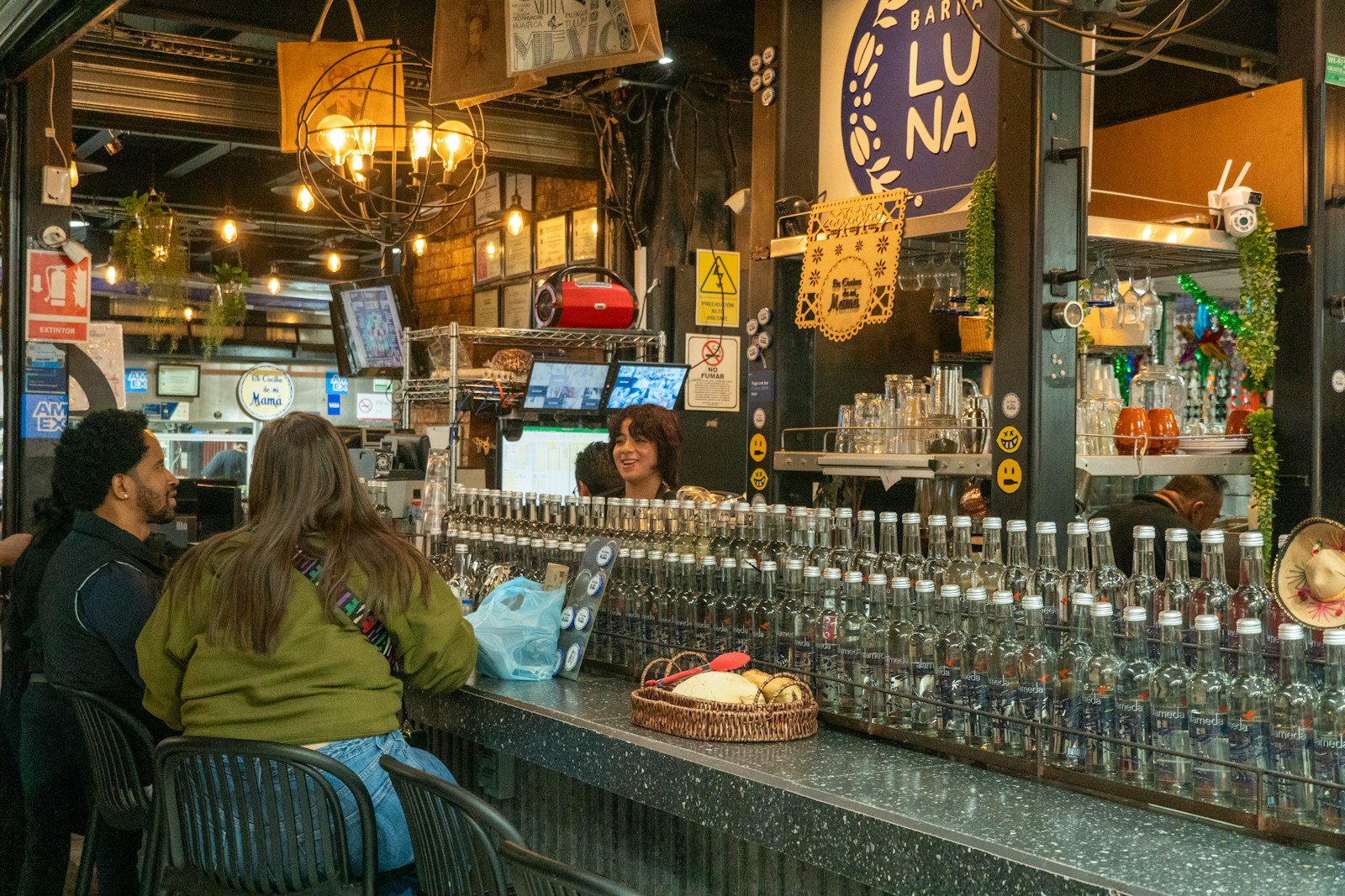 People sitting at a bar with bottles behind the bar.
