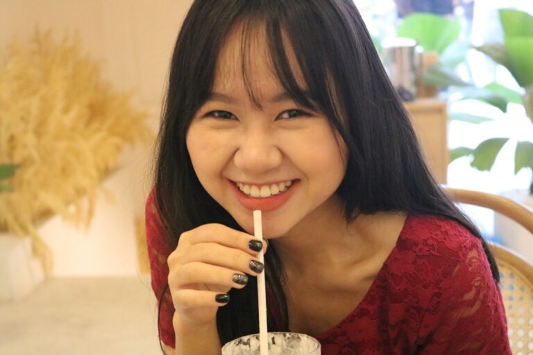 woman in red floral dress holding clear drinking glass