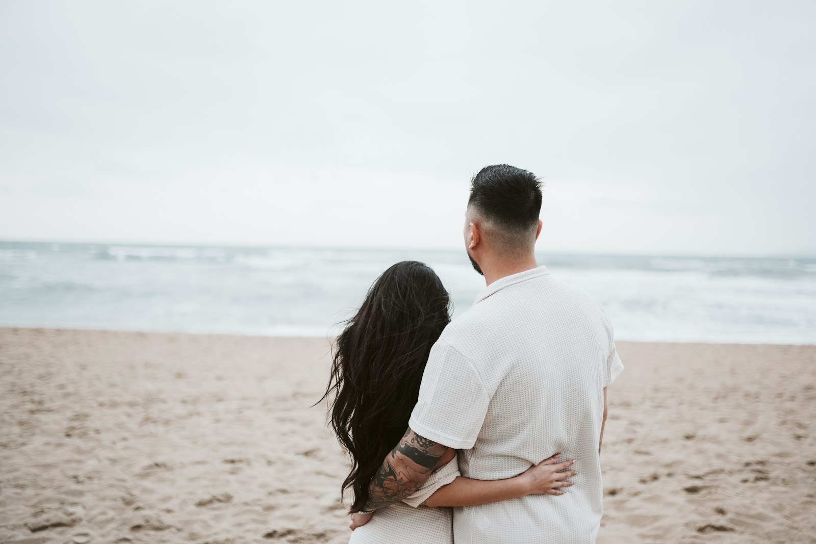Couple embracing on a beach looking at the ocean