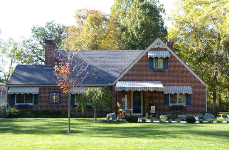 A brick house with a green lawn and trees.