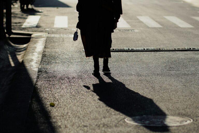 woman in black coat walking on the street during daytime