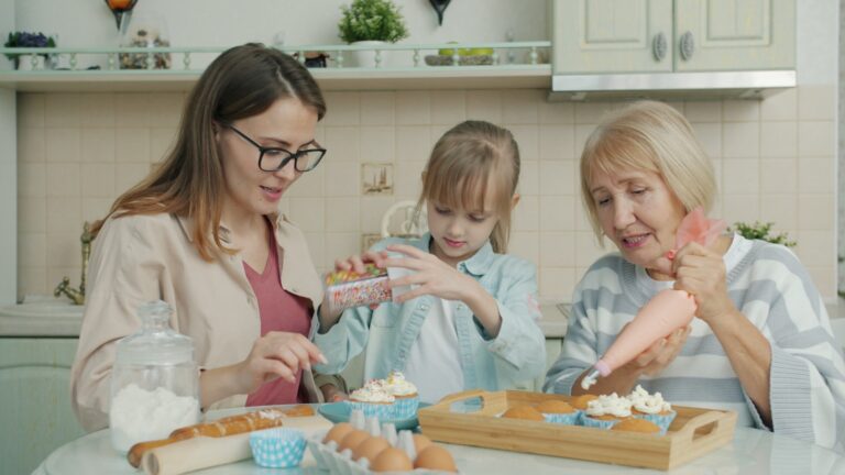 Three women baking and decorating cupcakes in a kitchen.