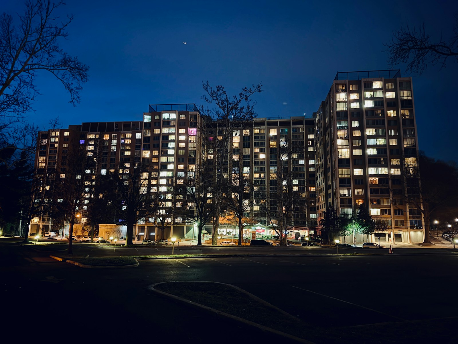 Apartment building illuminated at night with many lit windows.