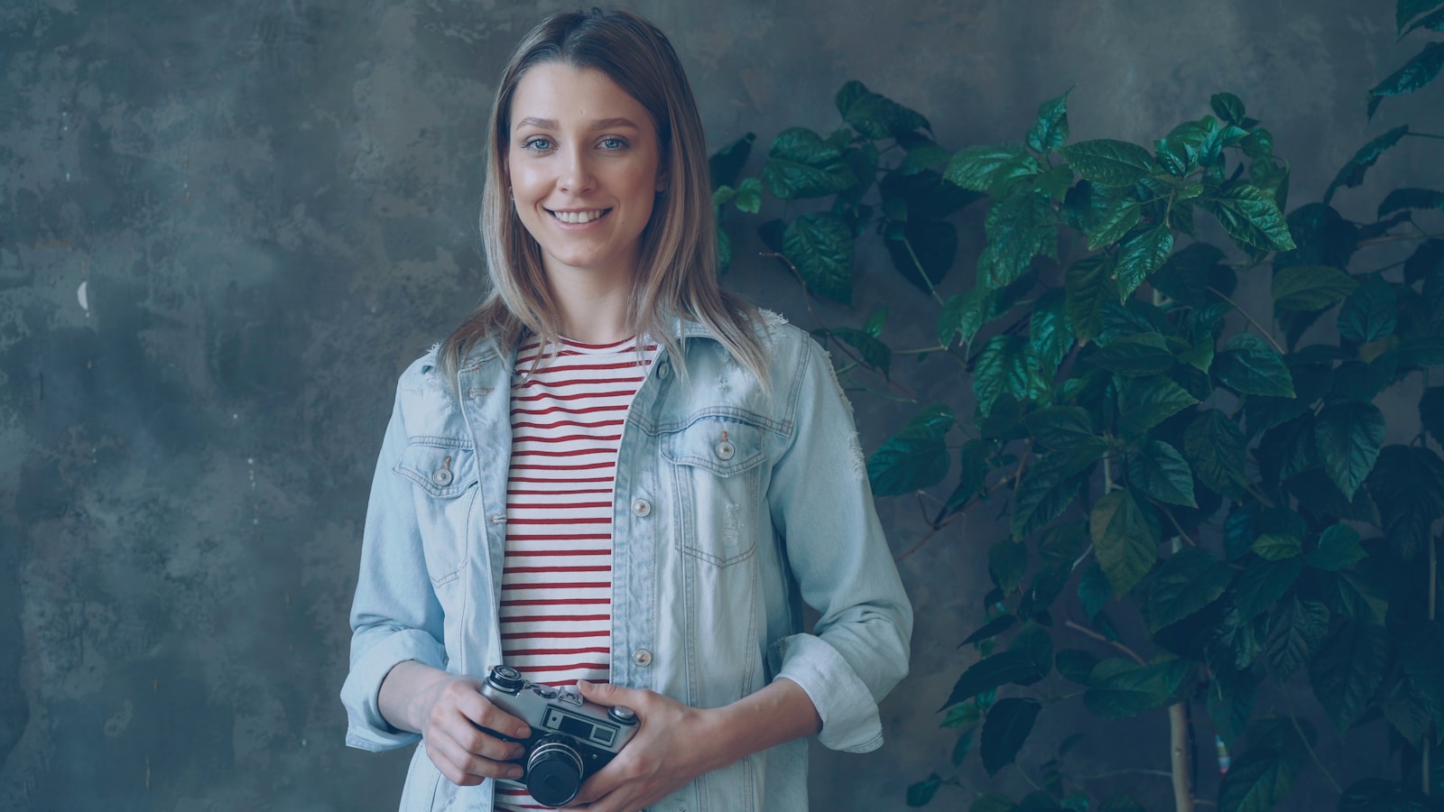 Woman smiles while holding a camera.