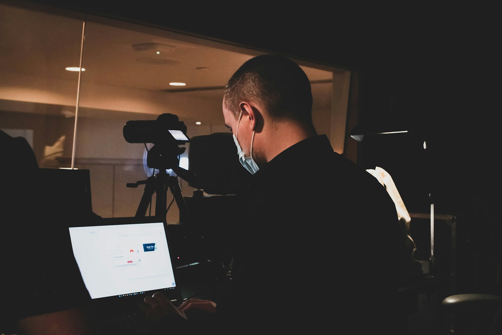 a man wearing headphones and sitting at a desk with a camera