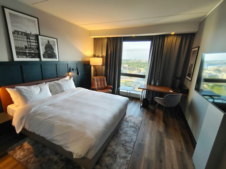 a large white bed sitting in a bedroom next to a window