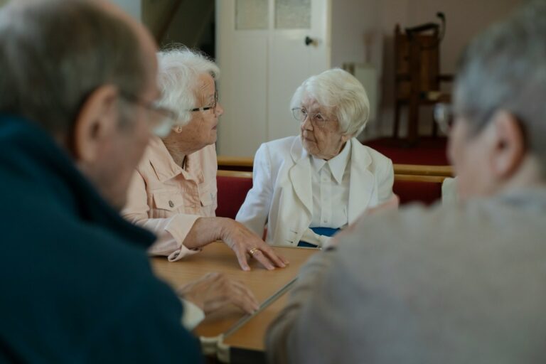 Seniors are sitting around a table, talking.