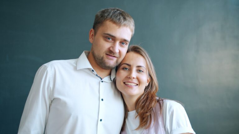 A couple smiling together against a dark background