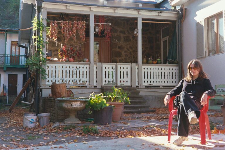 Woman sitting in red chair outside rustic house