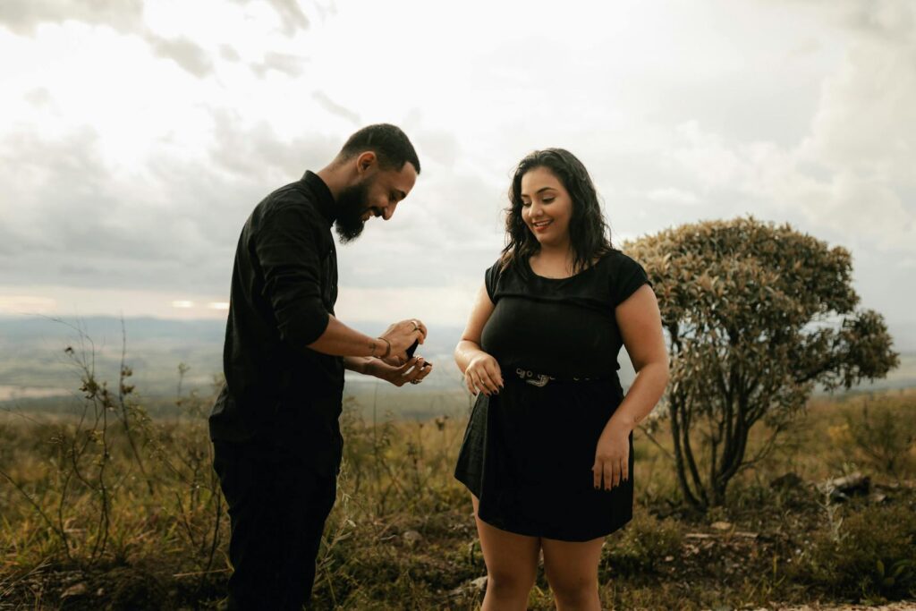A man proposes to his partner in a beautiful outdoor landscape, capturing a romantic and joyful moment.
