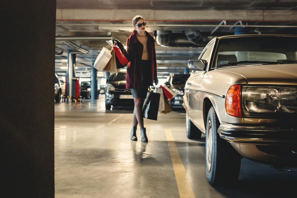 Elegant woman carrying shopping bags in an underground parking garage.