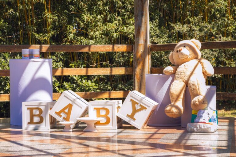Charming outdoor baby shower setup with teddy bear and decor boxes spelling 'BABY'.