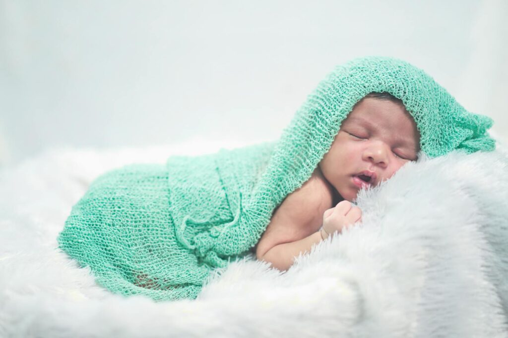 Serene image of a newborn baby wrapped in a soft green knit blanket, resting peacefully.