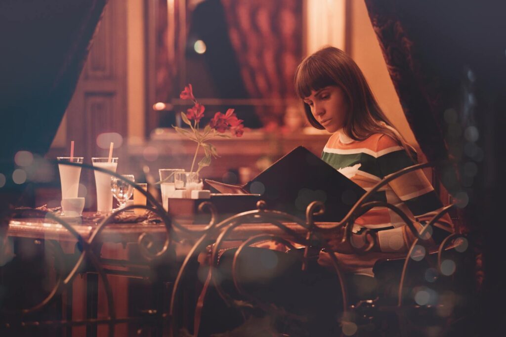 A woman sits in a cozy restaurant, enjoying an elegant evening with ambient lighting.