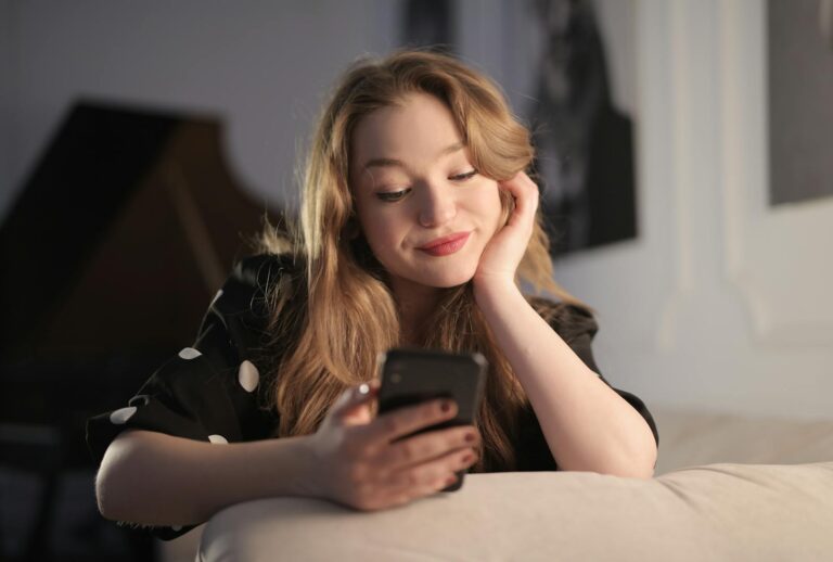 Smiling young woman enjoying leisure time on her smartphone in a cozy living room.