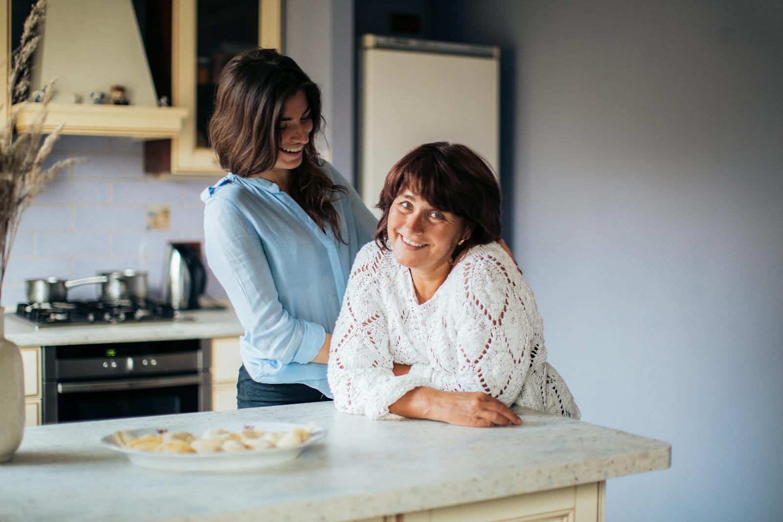 Happy mother and daughter bonding in a cozy kitchen setting, sharing smiles and love.
