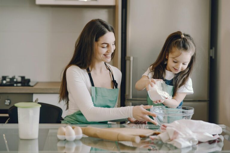 A joyful mother and daughter bonding while baking in the kitchen, smiling and enjoying the activity.