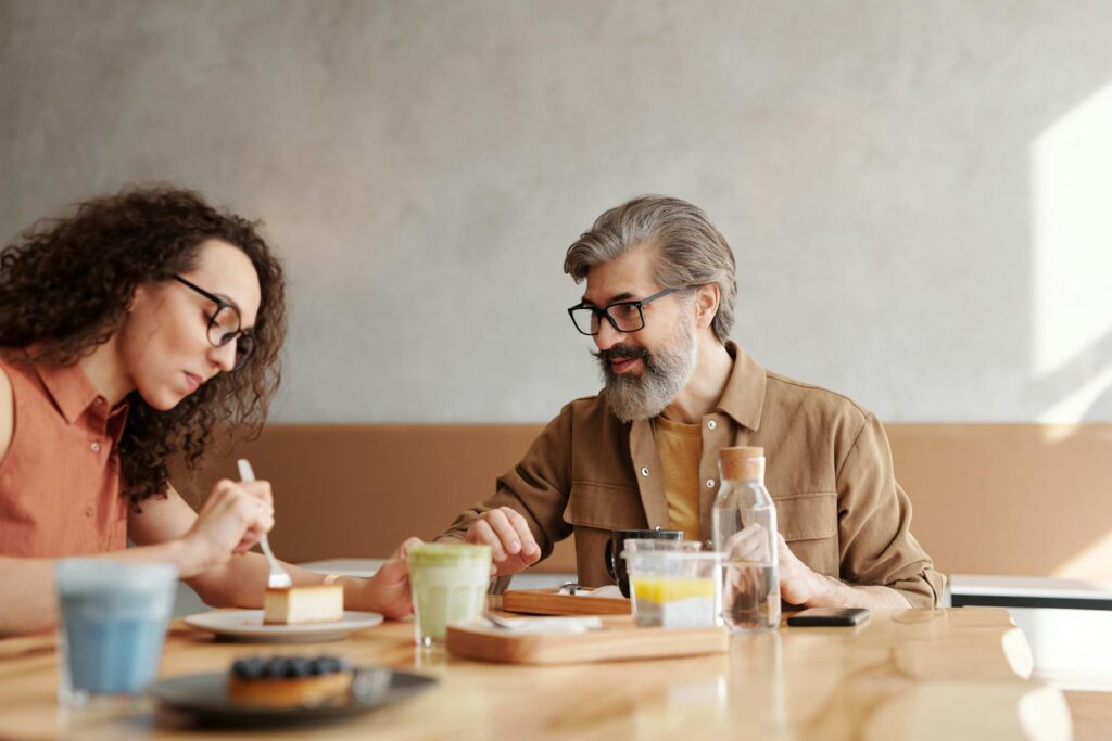 A man and woman enjoying desserts and drinks in a café setting, captured naturally.