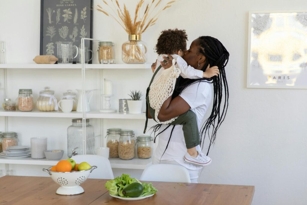 Caring mother holding child in a home kitchen with food and decorations.
