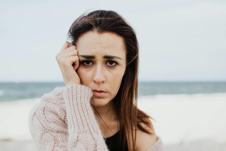 Portrait of a woman in a pensive mood, standing at the beach.