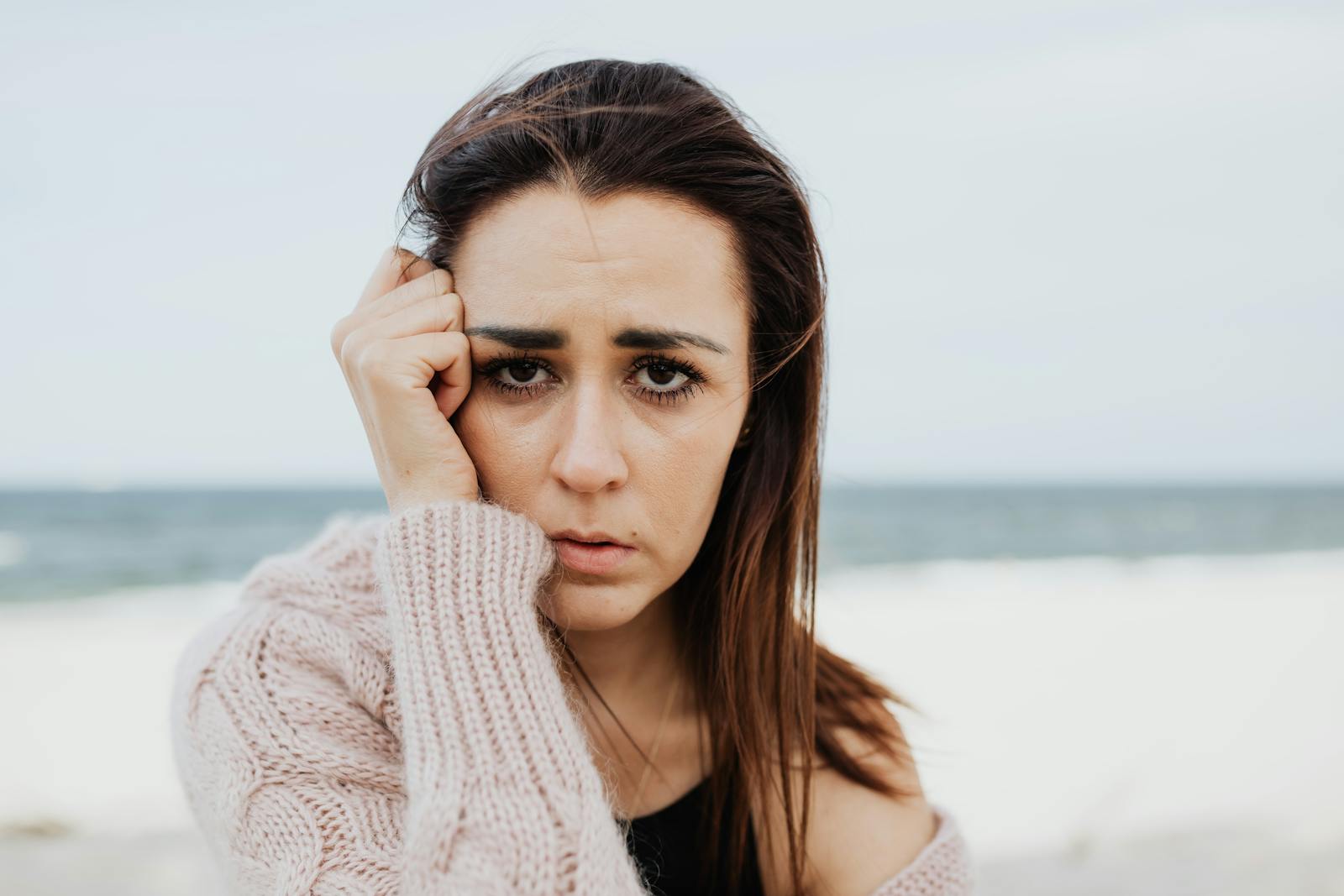 Portrait of a woman in a pensive mood, standing at the beach.