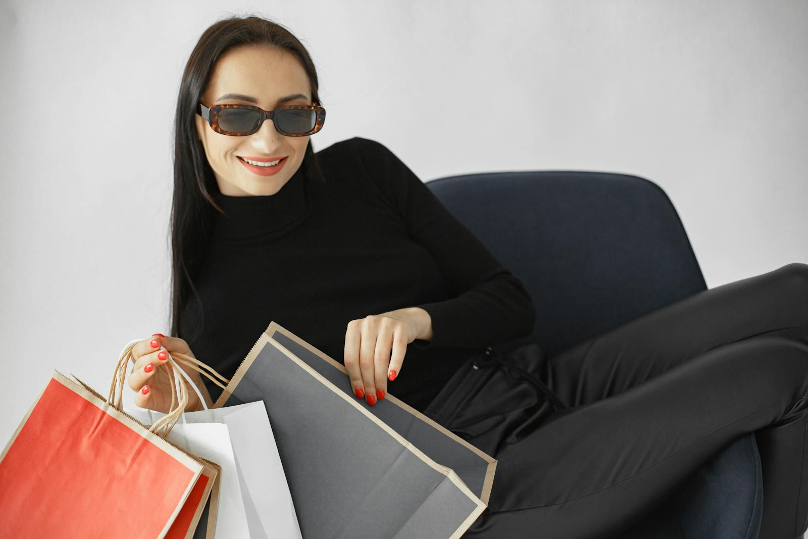 Stylish woman in sunglasses lounging with shopping bags, embodying relaxation and luxury.