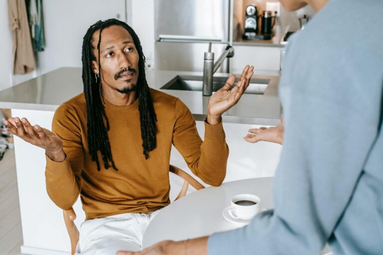 A couple in discussion at a kitchen table, capturing a serious moment in a relationship.