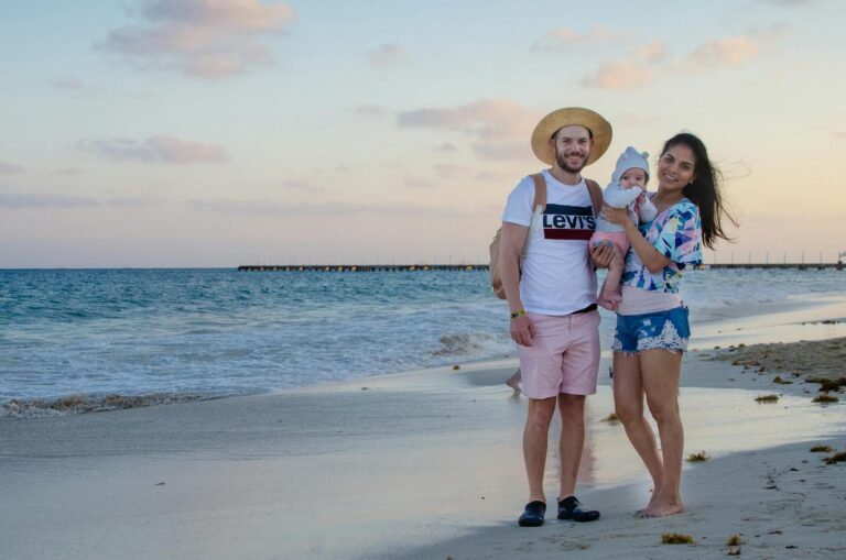 Smiling family enjoying beach vacation during beautiful sunset by the ocean.