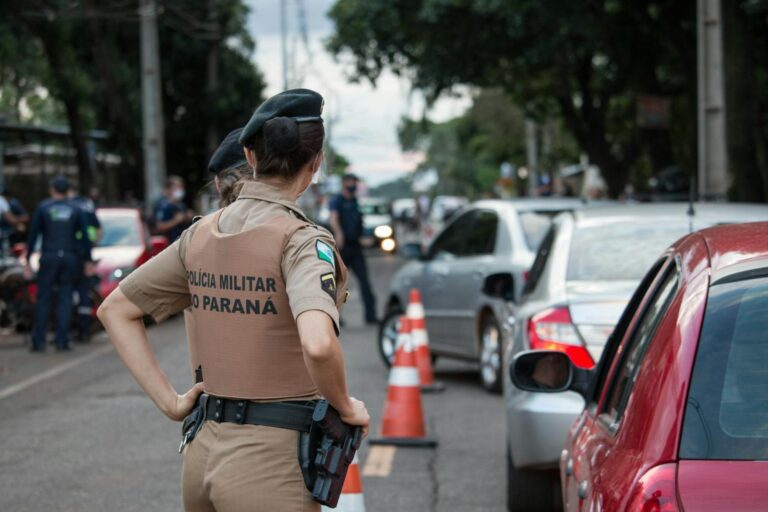 Back view of a police officer in uniform controlling traffic on a busy road.