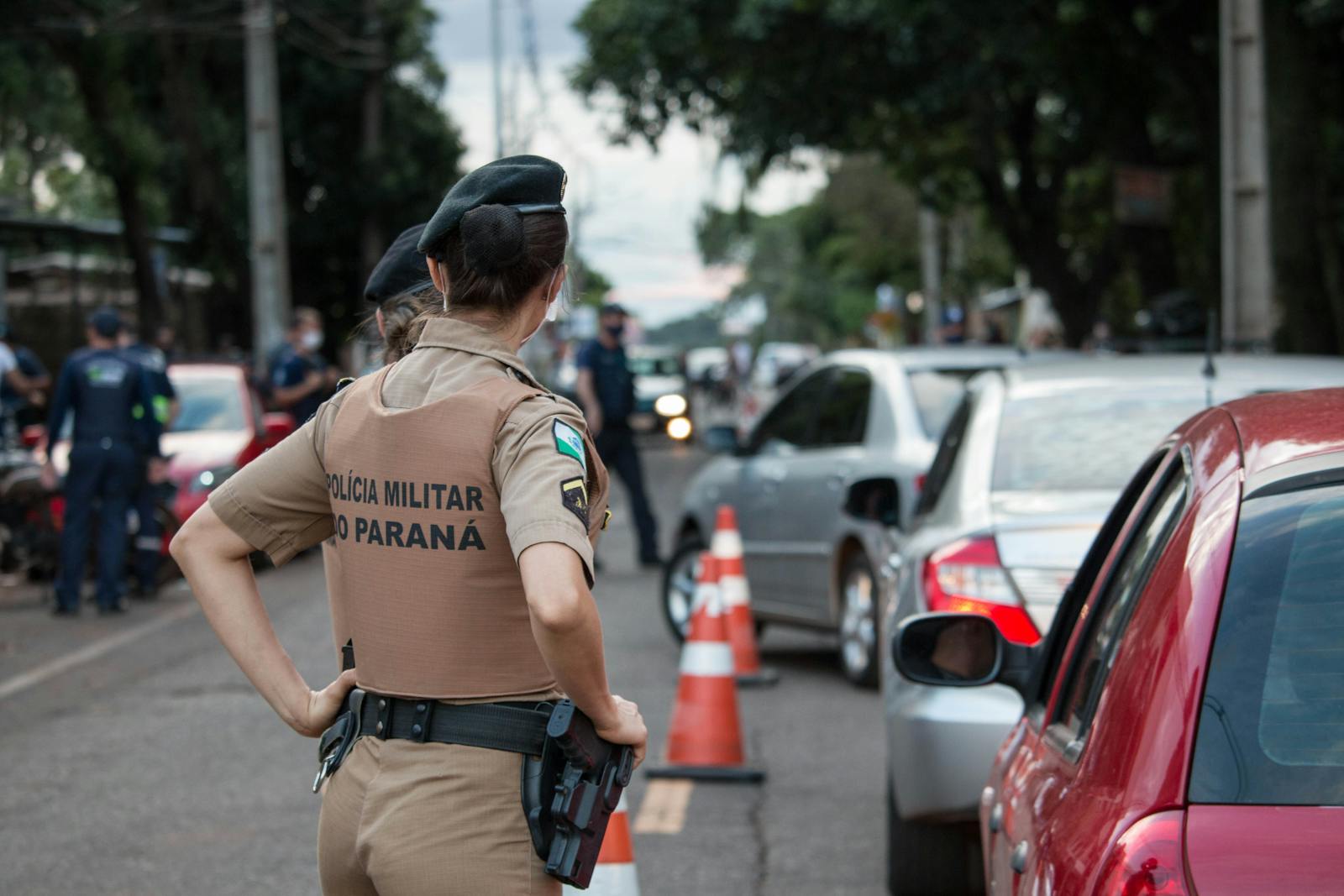 Back view of a police officer in uniform controlling traffic on a busy road.