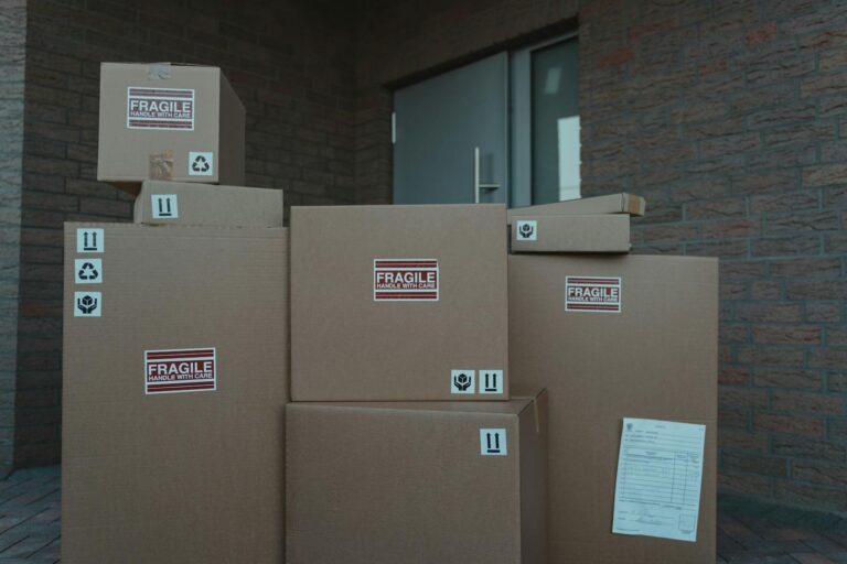 Several cardboard packages marked as fragile stacked at a building entrance.
