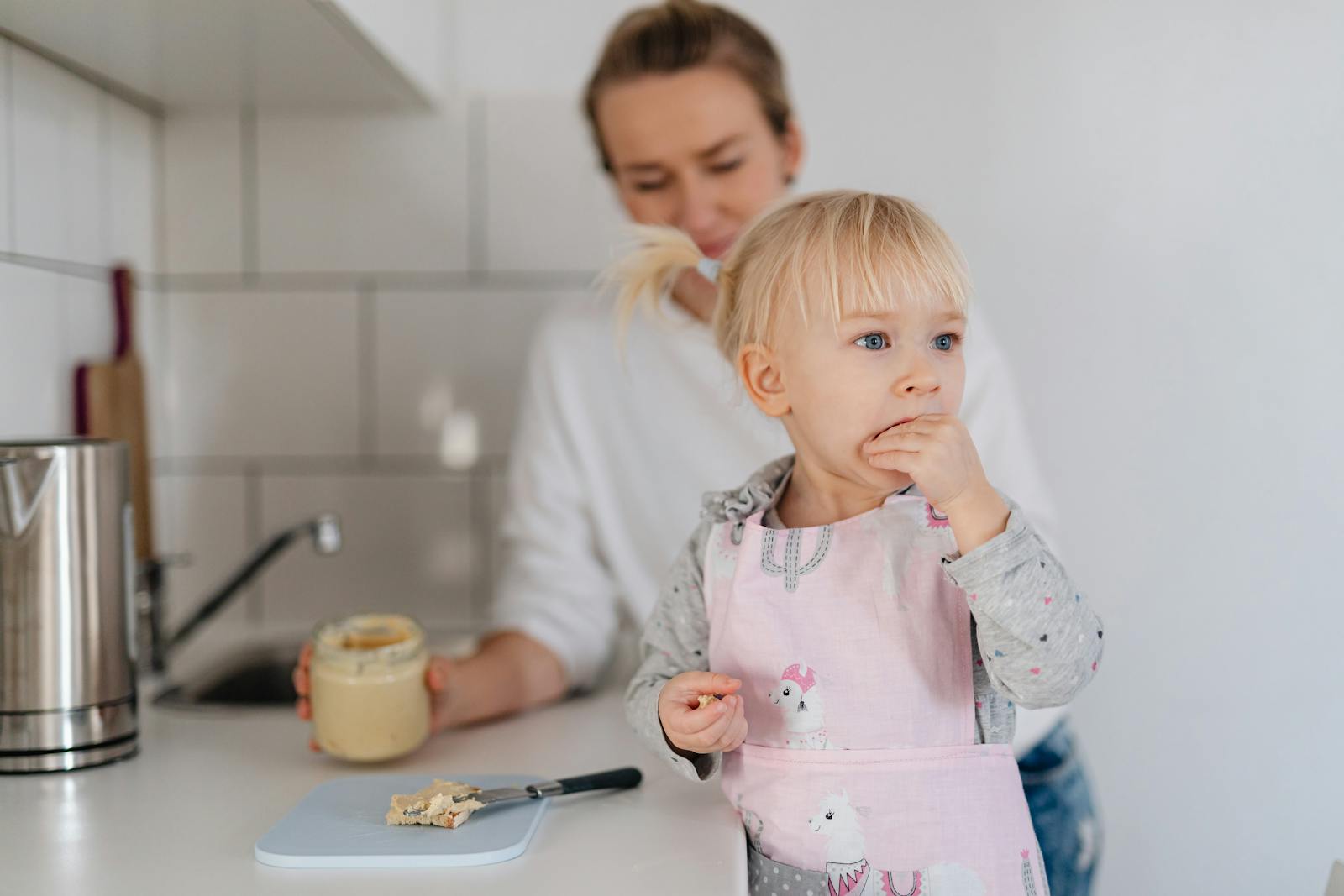 Mother and child enjoying snack time in a bright kitchen.