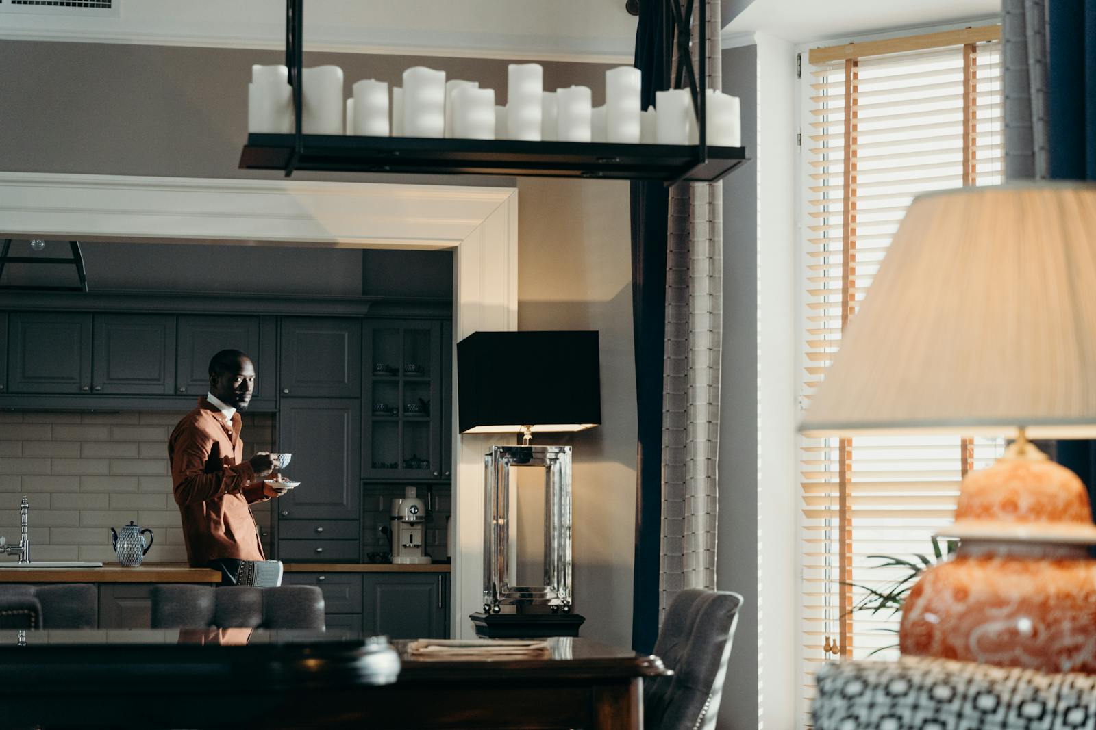 African man in a modern kitchen holding a coffee cup, enjoying a relaxed morning.
