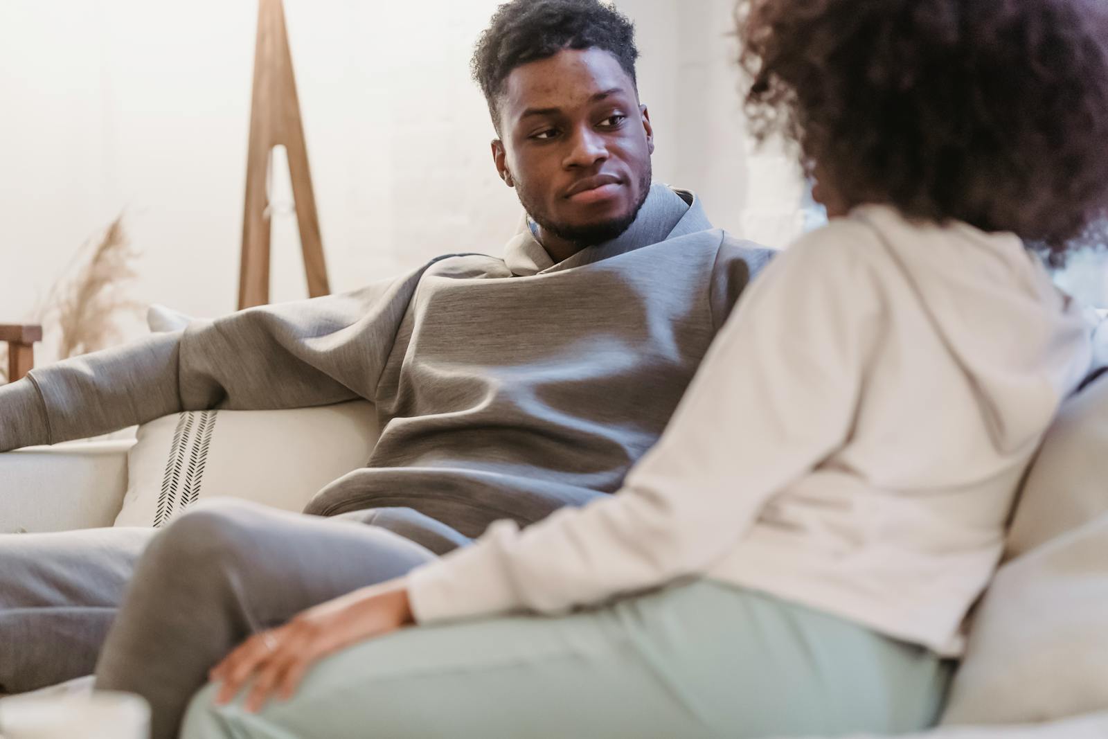 A couple relaxing on the couch at home, engaging in a thoughtful conversation.