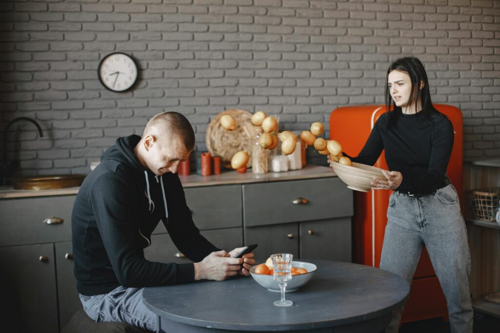 Tense moment in kitchen as couple argues, fruits scattered mid-air.