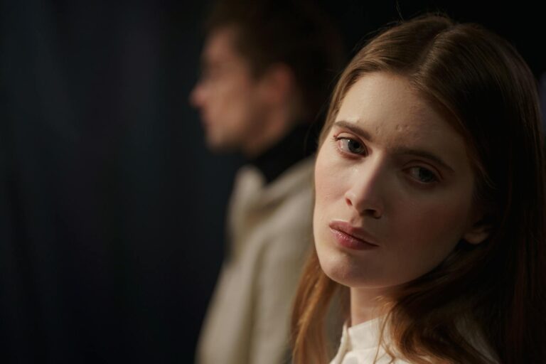 Close-up indoor portrait of a young woman displaying emotions, with a blurred background.