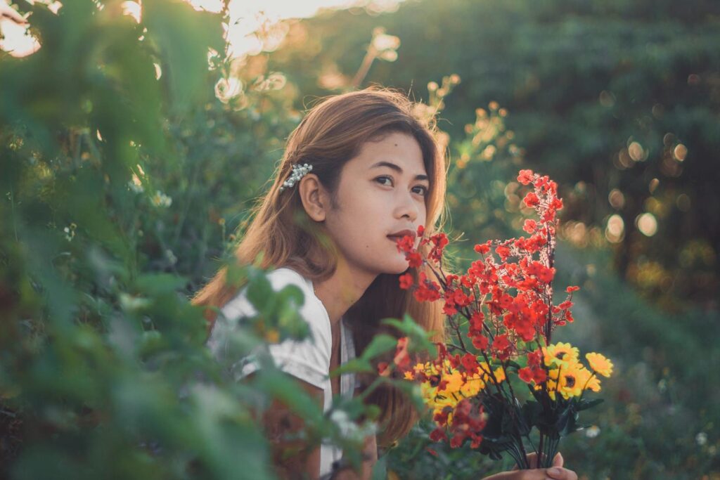 A young woman enjoys nature holding a vibrant bouquet of flowers in a lush garden.