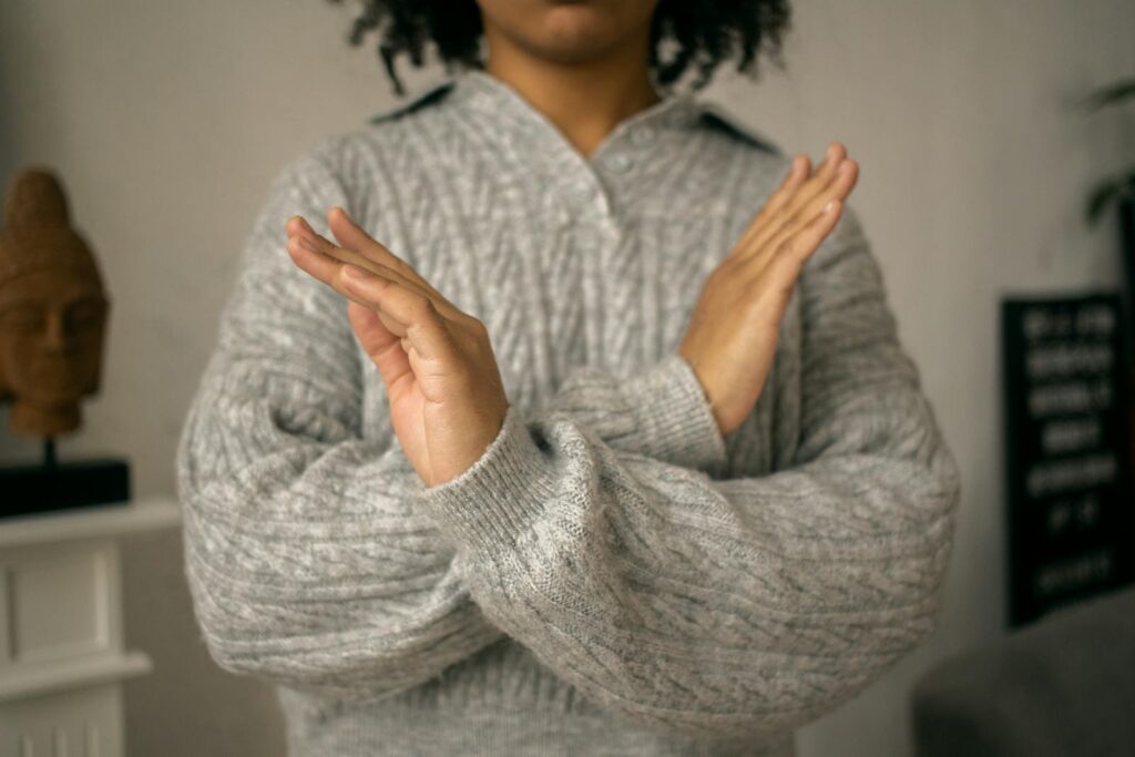 Close-up of a woman crossing her arms in a gesture of refusal, taken indoors.