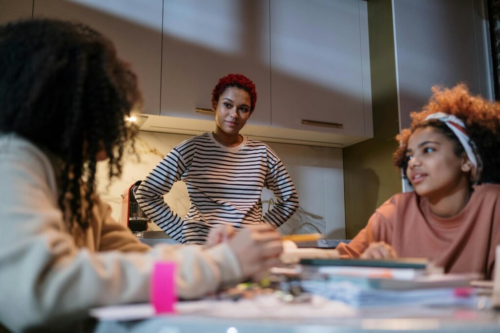 Three young black women working together indoors, fostering sisterhood and collaboration.