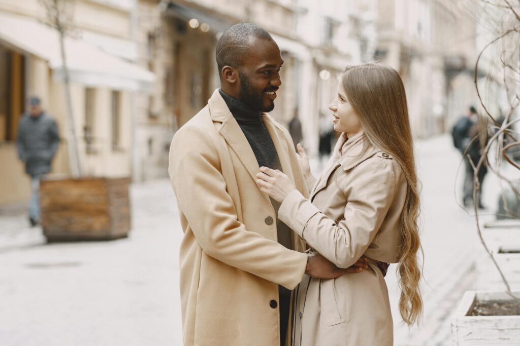 Happy interracial couple embracing outdoors in stylish winter clothing, expressing love and togetherness.