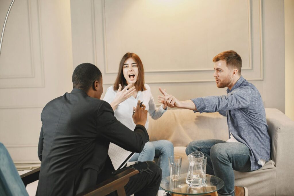 Three adults engaged in a lively discussion indoors, showcasing active communication and expression.