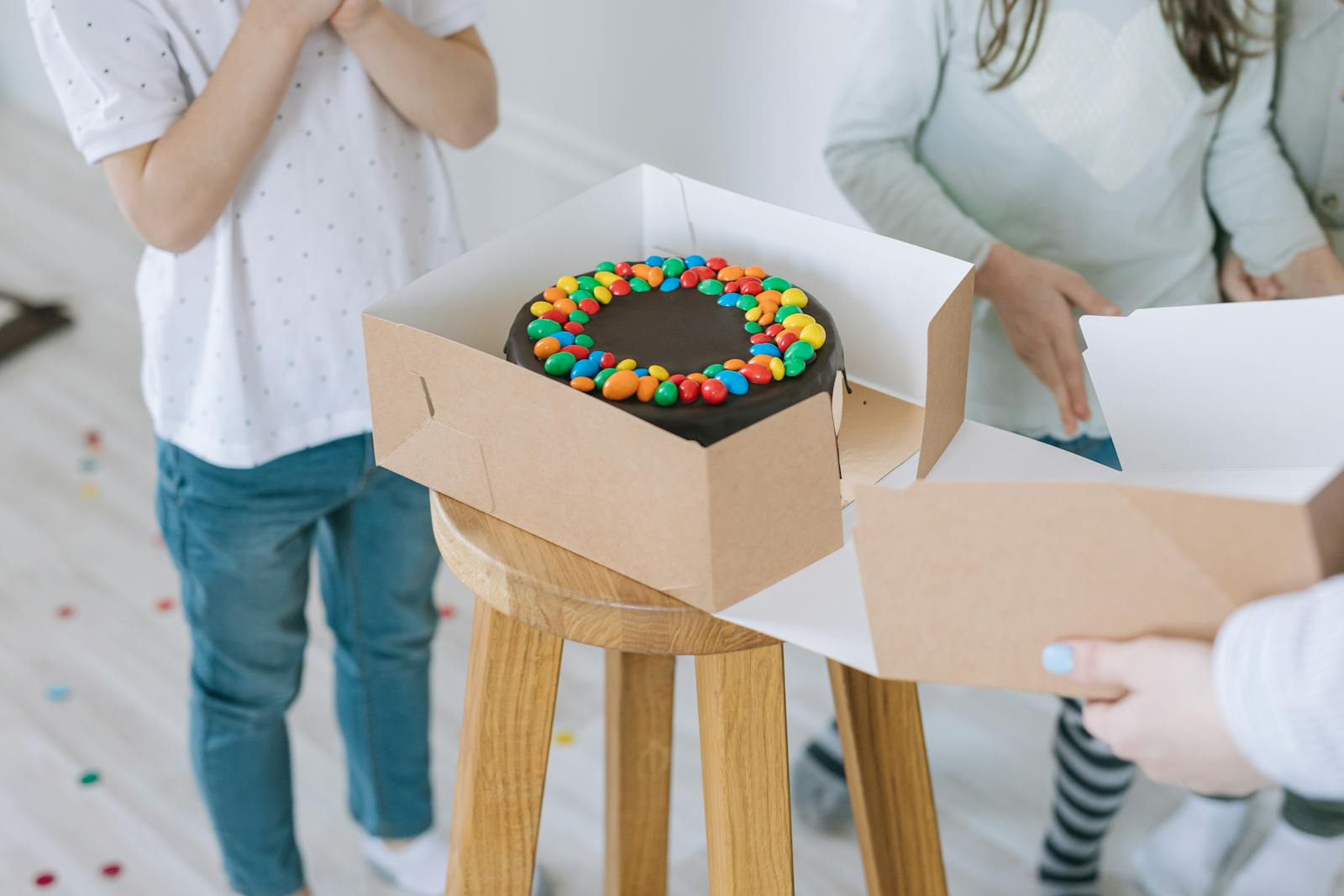 A delicious chocolate cake with colorful candy topping in a box, ready for celebration.