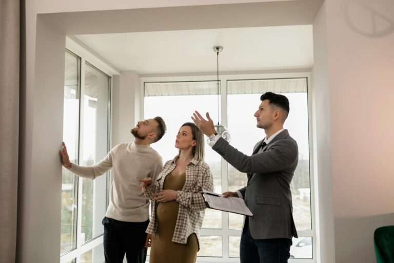 A young couple inspects a modern apartment with a real estate agent during a daytime viewing.