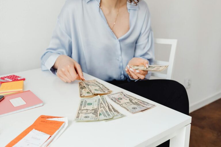 A woman counts US dollar bills at a desk, symbolizing finance management.