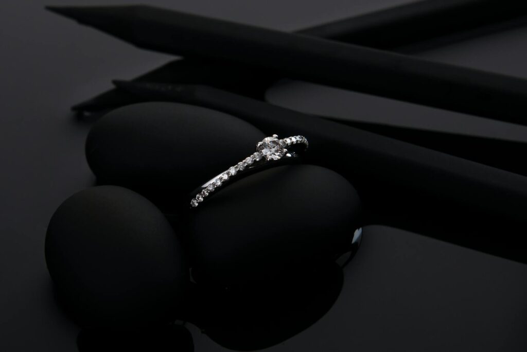 Sophisticated diamond engagement ring displayed stylishly on smooth black stones, perfect for luxury and jewelry themes.