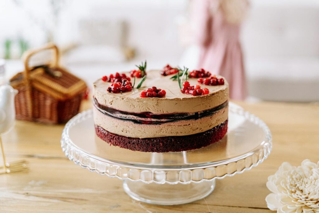 Delicious chocolate layered cake with berries on a glass stand indoors, perfect for celebrations.
