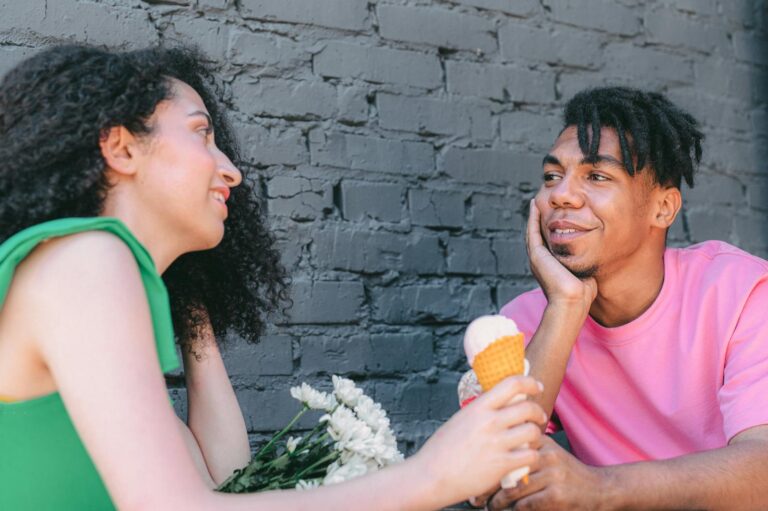 A couple shares a romantic moment with ice cream and flowers on a sunny day.