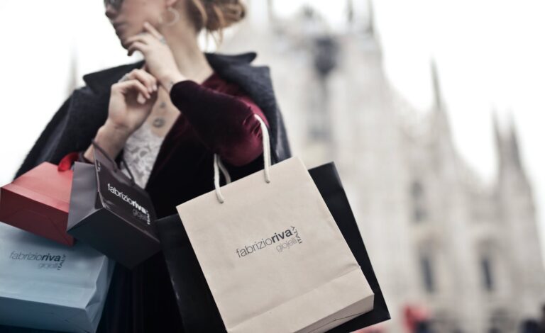 Stylish woman holding designer shopping bags near Milan's iconic Duomo. Urban fashion and lifestyle concept.