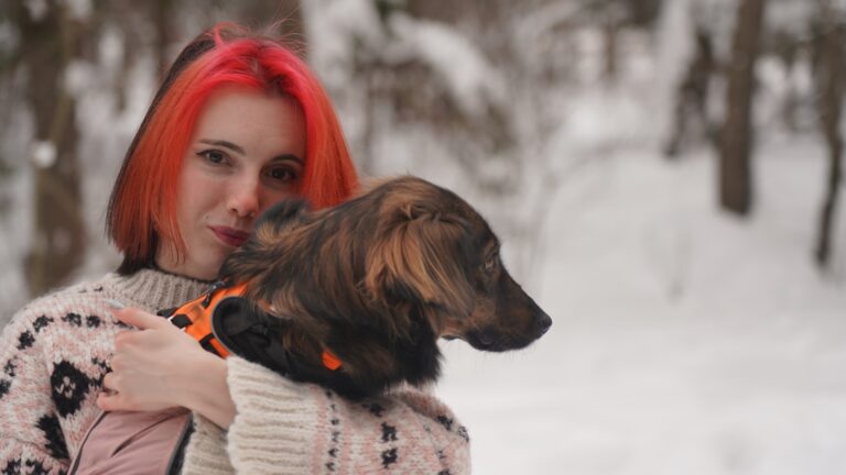 a woman holding a dog in her arms in the snow