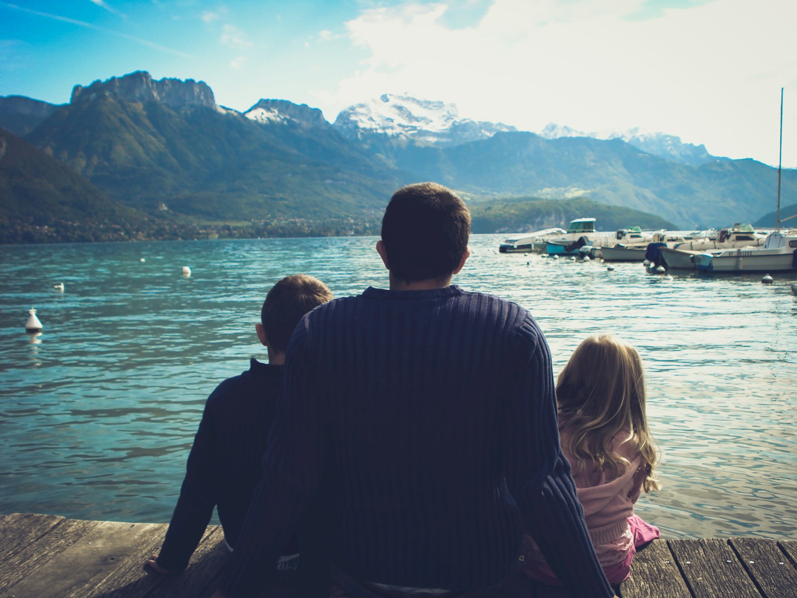 man and woman sitting on brown wooden dock during daytime